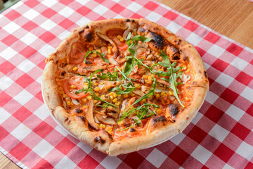 Delicious italian pizzas served on wooden table with red plaid table cloth.