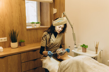 Beautiful young girl at the beautician does the spa procedures, facial massage and mask for the...