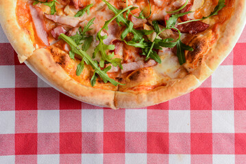 Delicious italian pizzas served on wooden table with red plaid table cloth.