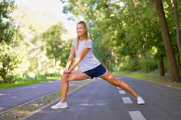 Woman runner stretching legs before exercising summer park  morning