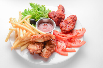 Roasted chicken wings and French fries isolated over white background. Served with fresh lettuce salad