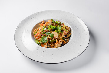 Sea food wok stir fry served in a white plate. Clams and shrimps wok isolated on white.