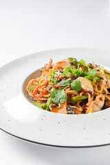Sea food wok stir fry served in a white plate. Clams and shrimps wok isolated on white.