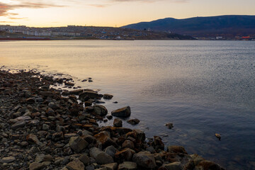 Morning seascape. View from the seashore to the water area of ​​the sea bay and the port town on the coast. Nagaev Bay, Sea of ​​Okhotsk, Magadan city, Magadan region, Siberia, Russian Far East.