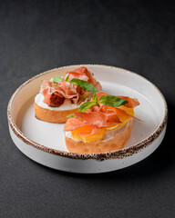 Juicy tomatoes and fresh fruit with carpaccio meat on fresh bread, sauce as topping. Traditional Italian cuisine.