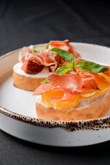Juicy tomatoes and fresh fruit with carpaccio meat on fresh bread, sauce as topping. Traditional Italian cuisine.