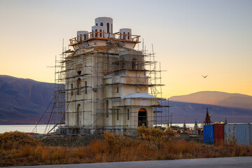 Construction of an Orthodox Church in the Far North of Russia in the Arctic. Church building in scaffolding. Beautiful sunrise over the mountains. Egvekinot, Chukotka, Russia. September, 2013. 