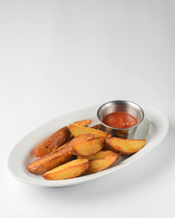 Roasted or baked potatoes with rosemary in a white bowl. Potatoes in rural style served with sauce.