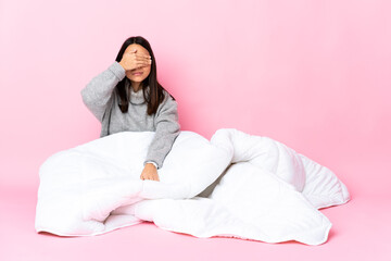 Young mixed race woman wearing pijama sitting on the floor covering eyes by hands. Do not want to...