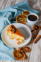 One piece of Caramel cake with pop corn on top served on a white plate. Dried oranges and a cup of Espresso coffee.
