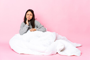 Young mixed race woman wearing pijama sitting on the floor with toothache
