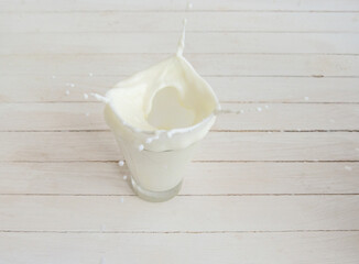 Fototapeta na wymiar White cow's milk in a clear glass on a light background. Drops
