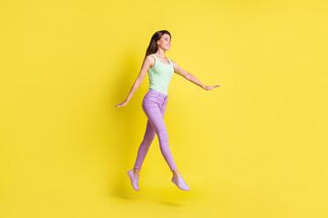 Fototapeta na wymiar Profile photo of girlish pretty lady go run empty space wear green top trousers sneakers isolated yellow color background