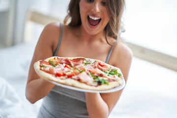 Beautiful adult woman eating pizza at home