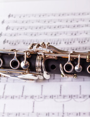 Obraz premium Clarinet on generic and unfocused score of scales and note positions. French model clarinet (Boehm standard keys)