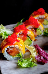 California roll of Salmon, avocado, flamed cheese leaf and tobiko. Vertical image.