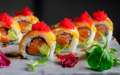 Close up of California Roll of Salmon, avocado, flamed cheese leaf and tobiko. Dark food