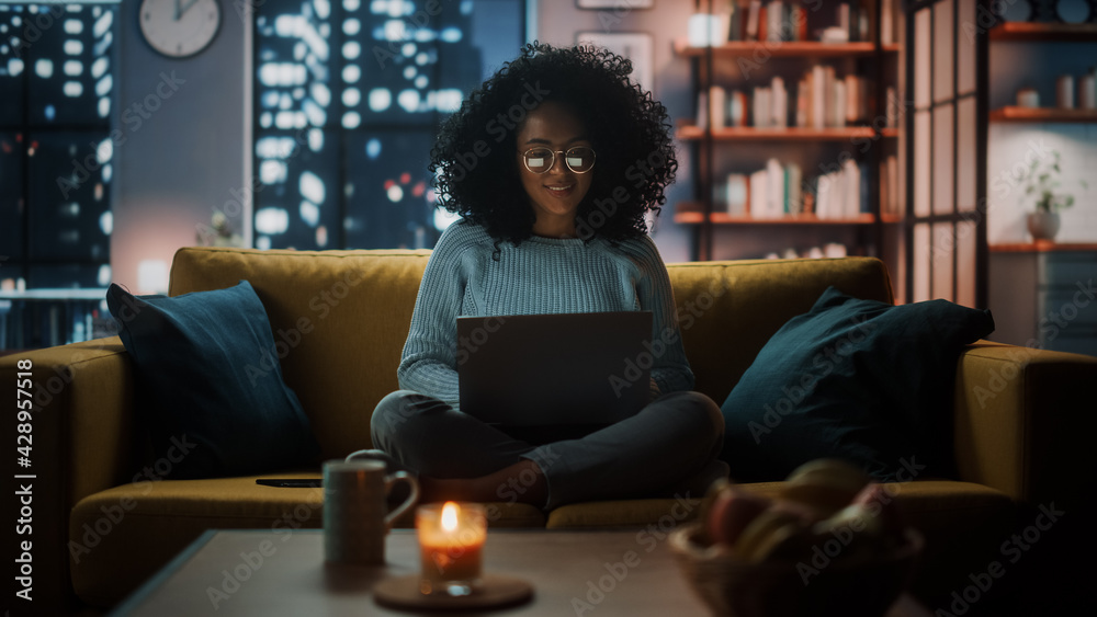 Poster beautiful authentic latina female sitting on couch sofa in a cozy dark living room in the evening an