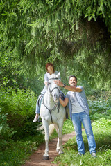 Obraz premium Kirov, Russia - August 07, 2020: Couple walking with white horse in forest in a nice summer day