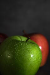 green and red apple on dark background