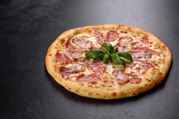 Delicious fresh crispy pizza from the oven with ham, cheese and basil