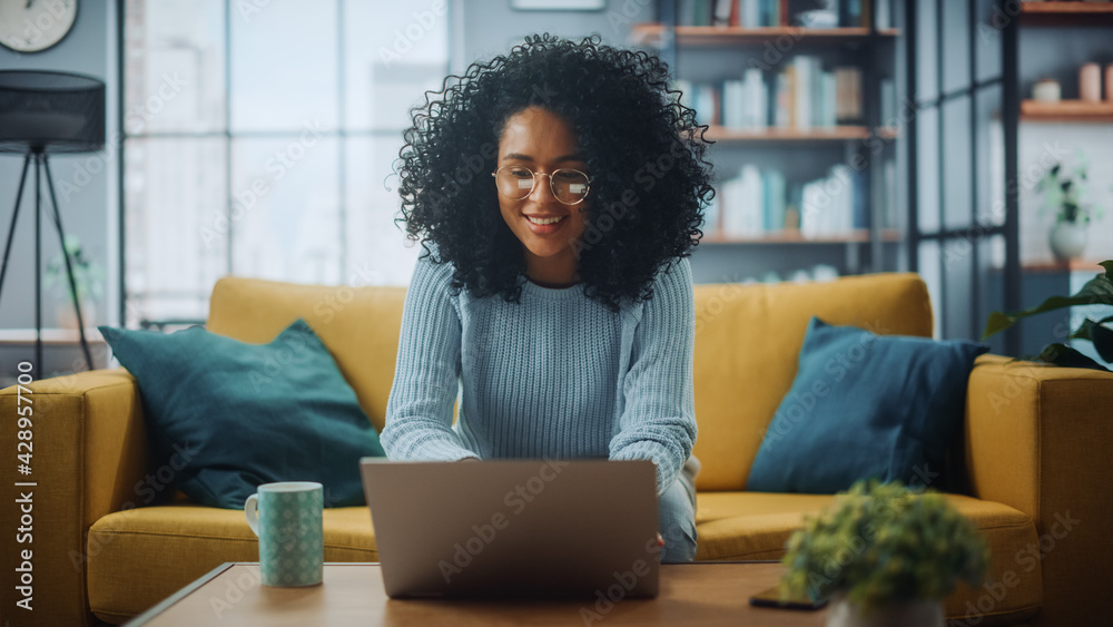 Poster portrait of a beautiful authentic latina female in a stylish cozy living room using laptop computer 