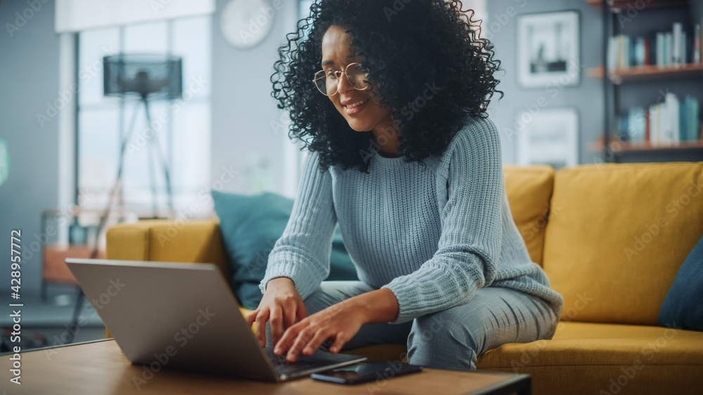 Poster portrait of a beautiful authentic latina female in a stylish cozy living room using laptop computer 