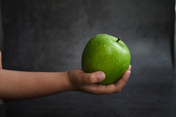 the girl holds a green apple in her hand