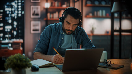 Handsome Caucasian Man With Headphones Talk on Video Conference Call on Laptop while Sitting in...