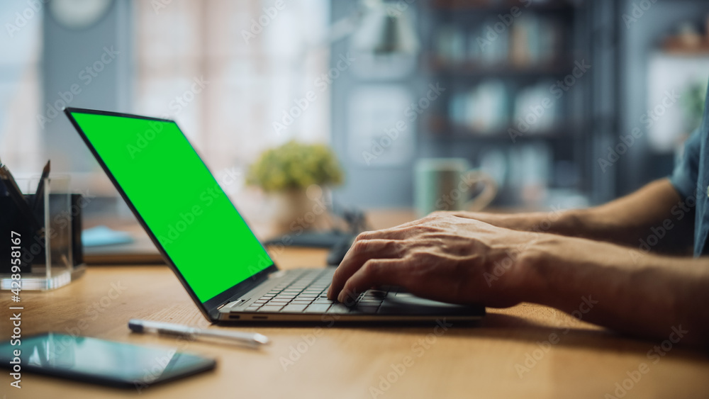 Poster close up on hands of a male specialist working on laptop computer with green screen mock up display 