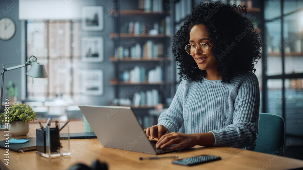 Poster beautiful authentic latina female sitting at a desk in a cozy living room and using laptop computer 
