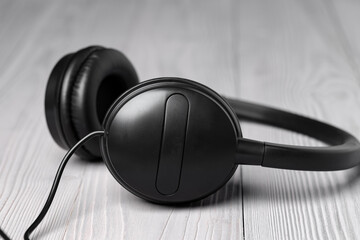 Black headphones with wire on wooden background