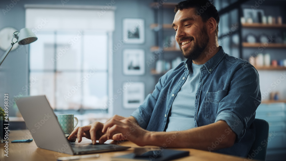 Poster handsome caucasian man working on laptop computer while sitting on a sofa couch in stylish cozy livi