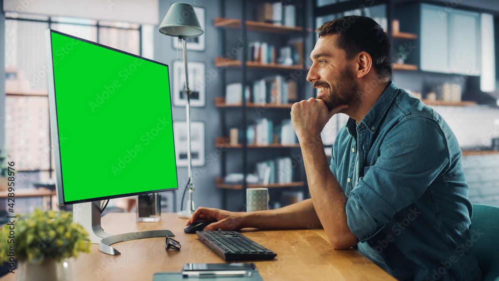 Poster Handsome Caucasian Specialist Working on Desktop Computer with Green Screen Mock Up Display at Home Living Room. Freelance Man Chatting to Clients Over the Internet on Social Networks.