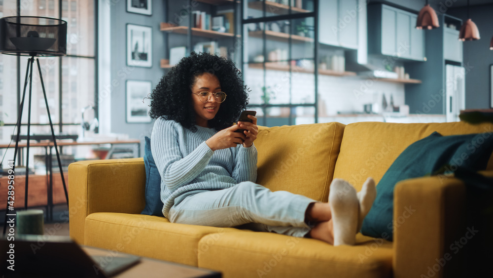 Aufkleber happy beautiful latina female using smartphone in cozy living room at home. female resting on comfor