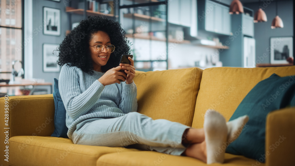 Poster happy beautiful latina female using smartphone in cozy living room at home. female resting on comfor