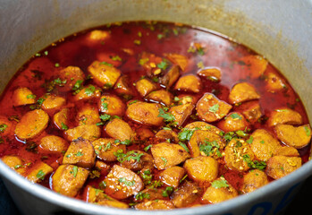 Spicy Dum Aloo In A Large Container. Kashmiri dum aloo or spicy potato curry, oily dish served in a large container in weddings. Background concept for Indian vegetarian regional foods bengali.