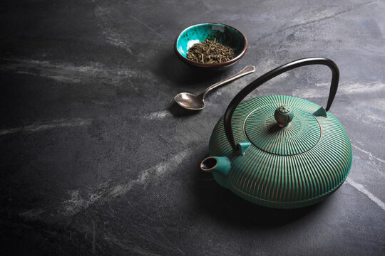 Beautiful green japanese cast iron teapot and dry tea leaves