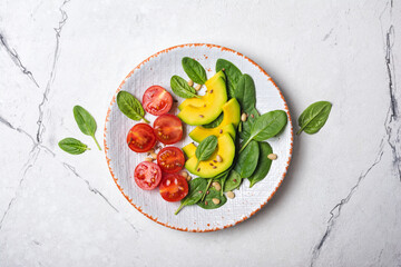 Healthy vegetarian salad with fresh baby spinach, cherry tomatoes, avocado and pine nuts
