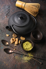 Green matcha tea in cups or bowls with bamboo whisk and traditional black asian kettle