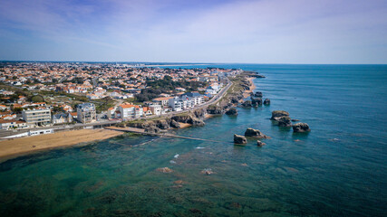 Aerial view from a magnificent coastline between cliffs, beaches, clear water and city. That place is called "Les 5 pineaux" located in Saint-Hilaire-de-Riez, France