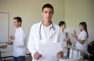  Medical students in patient's hospital room. Portrait of young student. Focus is on foreground. Space for copy.