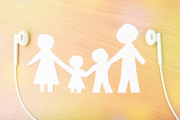 family made of paper, a symbol of a happy strong family, on a wooden background and headphones. children's Day, family day.