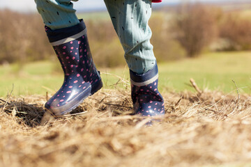 Child stands in the straw with rubber boots.
Kind steht mit Gummistiefeln im Stroh.