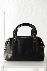 closed rectangular black leather bag with gold jewelry 