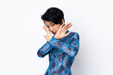 Young Vietnamese woman with short hair wearing a traditional dress over isolated white background nervous stretching hands to the front