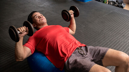 A fit and handsome asian guy does Stability Ball Dumbbell Chest