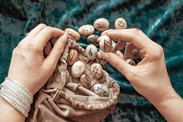 stone runes in the hands of a young woman and candles on a blue velvet background, concept of...