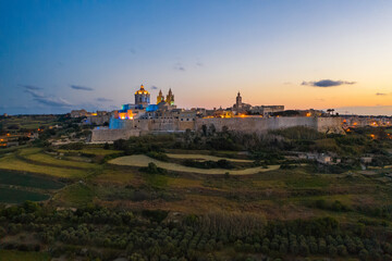 Mdina city - old capital of Malta. Evening, nature landscape, sunset sky. Colourful lights in the city