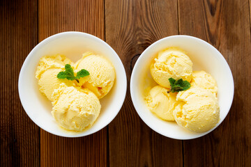 Vanilla ice cream scoops sundae in bowl on wooden background